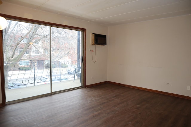 unfurnished room featuring dark wood-type flooring and a wall unit AC