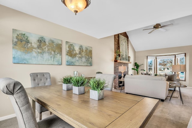 dining area featuring a large fireplace, ceiling fan, vaulted ceiling, and carpet flooring