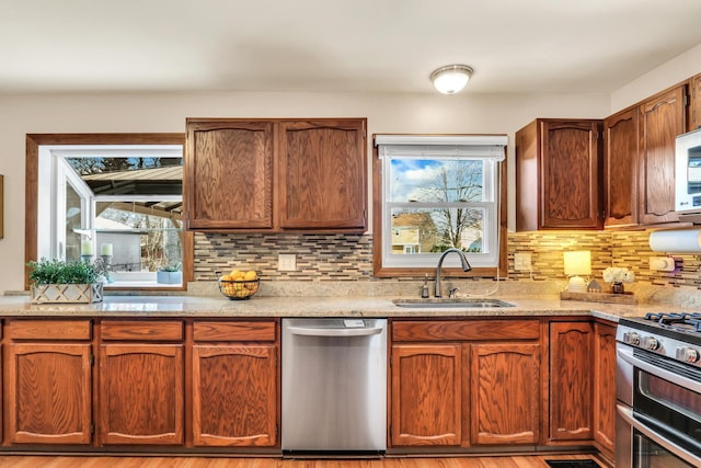 kitchen featuring appliances with stainless steel finishes, light hardwood / wood-style floors, decorative backsplash, and sink