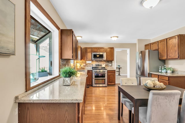 kitchen featuring sink, light wood-type flooring, backsplash, and appliances with stainless steel finishes