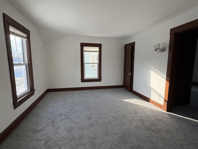 carpeted empty room featuring lofted ceiling