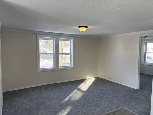 empty room featuring a textured ceiling and dark colored carpet