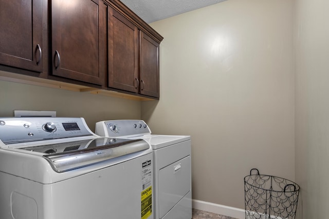 washroom featuring a textured ceiling, cabinets, and washing machine and clothes dryer