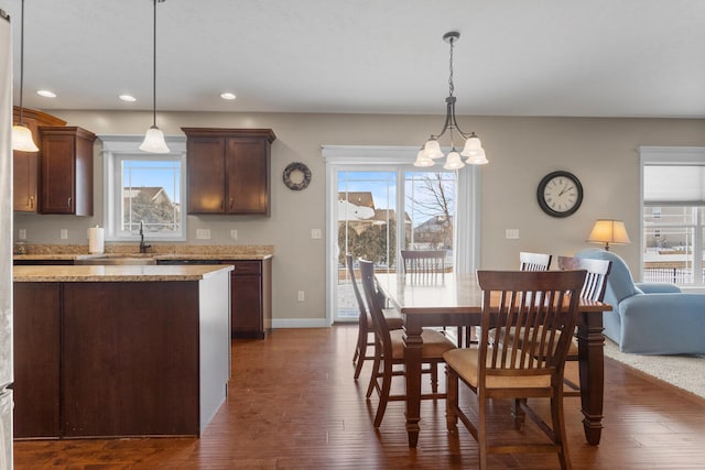 dining room with dark wood-type flooring, a chandelier, and sink