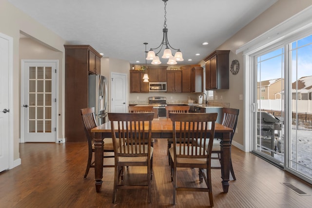 dining space with sink, an inviting chandelier, and dark hardwood / wood-style floors