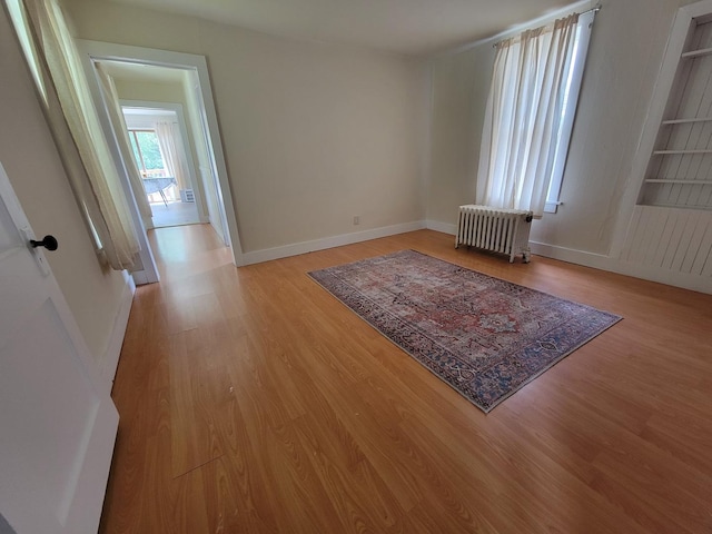 407 E Walnut St, Oglesby, IL 61348 - empty room featuring radiator, light wood-style floors, baseboards, and built in shelves