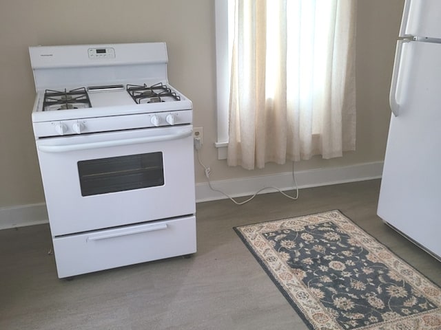 kitchen featuring white appliances and dark hardwood / wood-style flooring