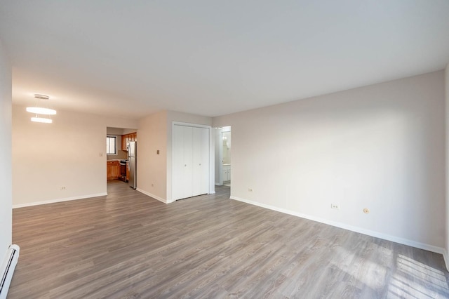 spare room with a baseboard heating unit and light hardwood / wood-style flooring