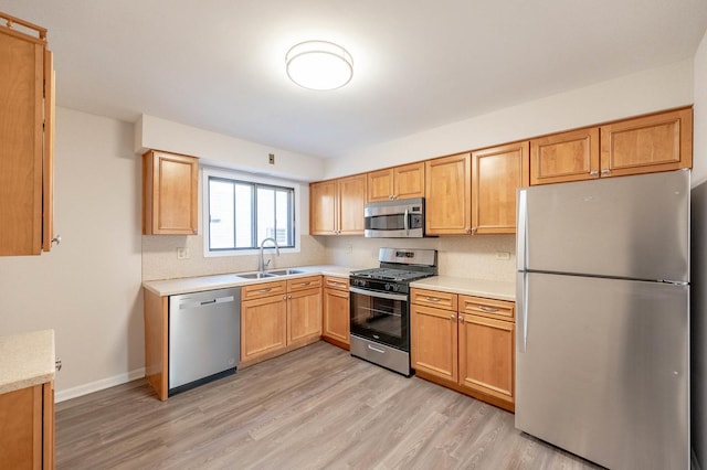 kitchen with appliances with stainless steel finishes, decorative backsplash, light hardwood / wood-style floors, and sink