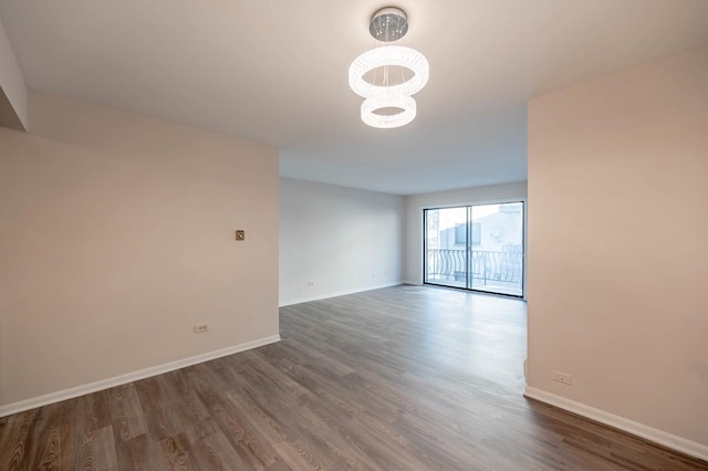 spare room with dark hardwood / wood-style floors and a notable chandelier