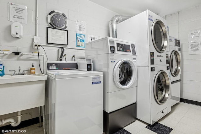 laundry area with washing machine and dryer, stacked washer and clothes dryer, and sink