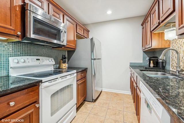 kitchen with stainless steel appliances, dark stone countertops, decorative backsplash, sink, and light tile patterned floors