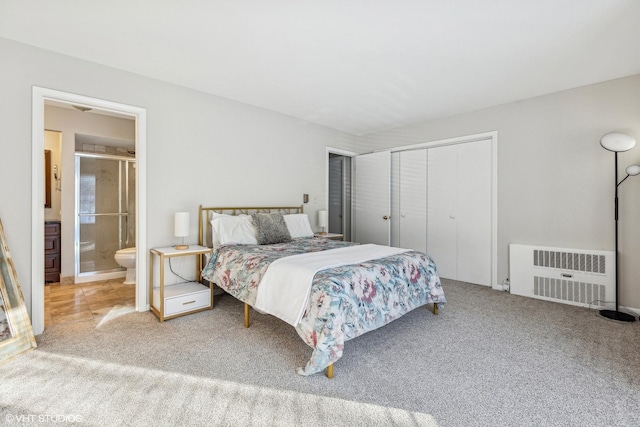 carpeted bedroom featuring a closet, radiator heating unit, and ensuite bath