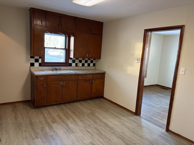 kitchen featuring tasteful backsplash, sink, and light wood-type flooring