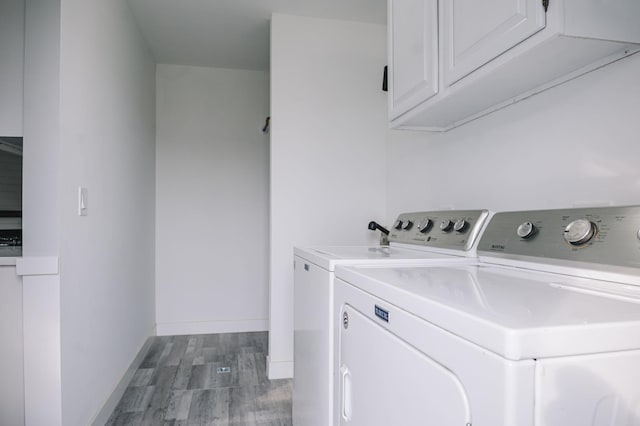 laundry room with washer and dryer, cabinets, and hardwood / wood-style floors