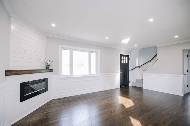 unfurnished living room featuring a large fireplace, ornamental molding, and dark hardwood / wood-style flooring