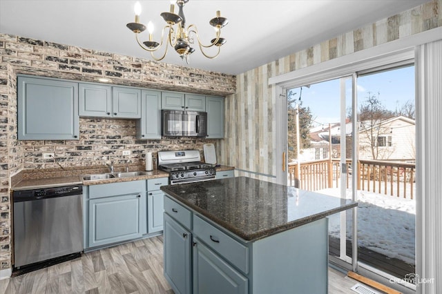 kitchen featuring stainless steel appliances, a center island, pendant lighting, sink, and an inviting chandelier