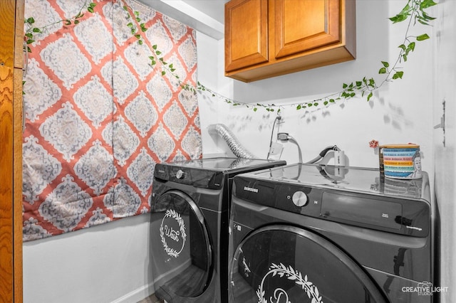 clothes washing area featuring cabinets and washer and clothes dryer