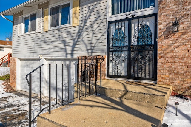 snow covered property entrance with a garage