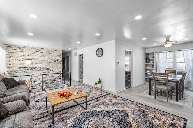 living room with brick wall, ceiling fan, and light hardwood / wood-style flooring