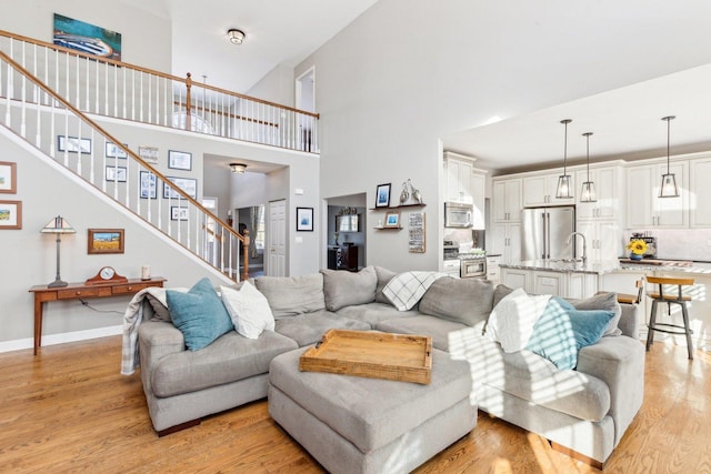 living room with a high ceiling, sink, and light hardwood / wood-style floors