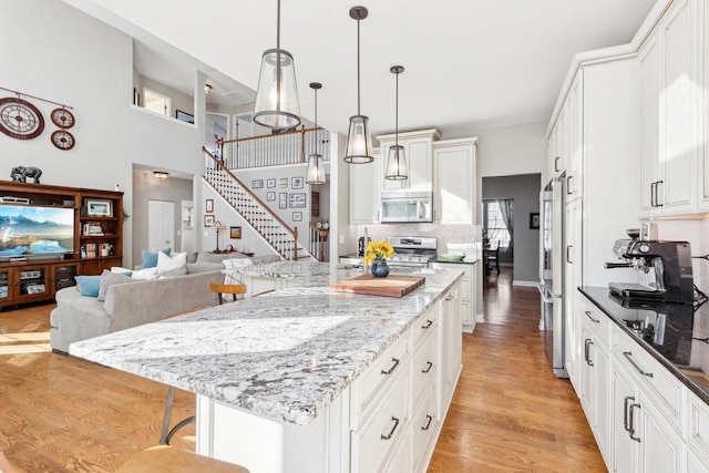 kitchen featuring hanging light fixtures, a kitchen island, appliances with stainless steel finishes, and a breakfast bar area