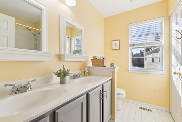 bathroom with tile patterned flooring, vanity, a wealth of natural light, and toilet