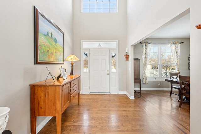 entrance foyer featuring a towering ceiling and light wood-type flooring