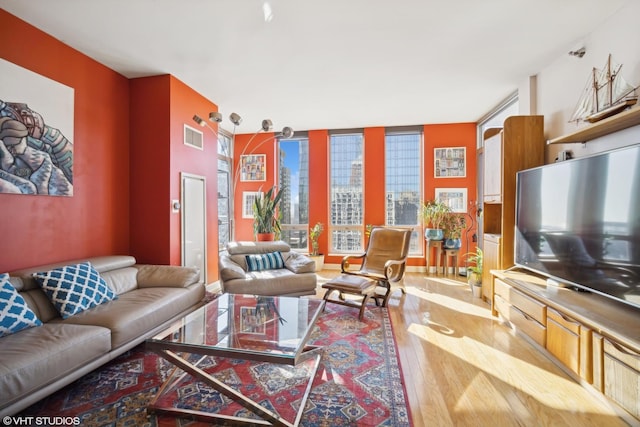 living area with a wall of windows, visible vents, and wood finished floors