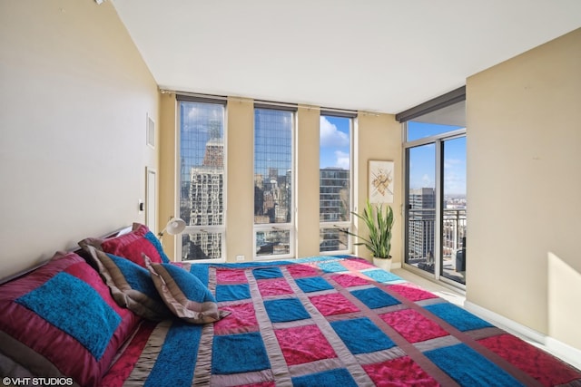 bedroom featuring baseboards, access to outside, floor to ceiling windows, and a city view