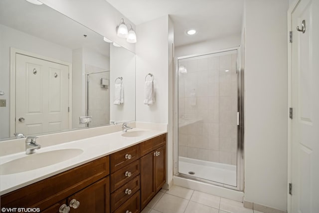 bathroom featuring double vanity, a shower stall, a sink, and tile patterned floors