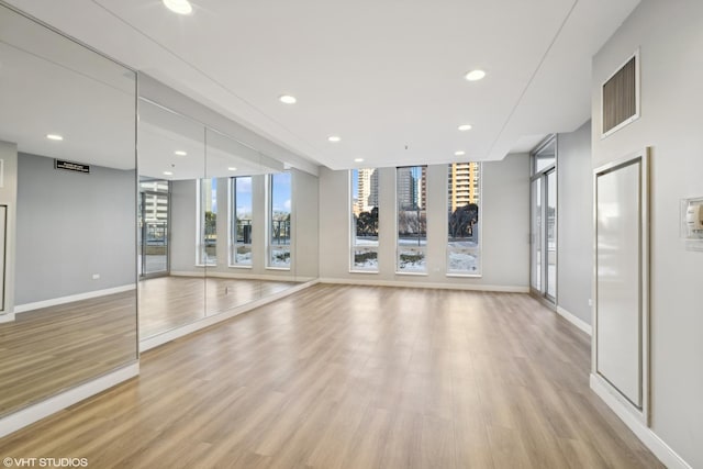 interior space featuring expansive windows, recessed lighting, light wood-type flooring, and baseboards