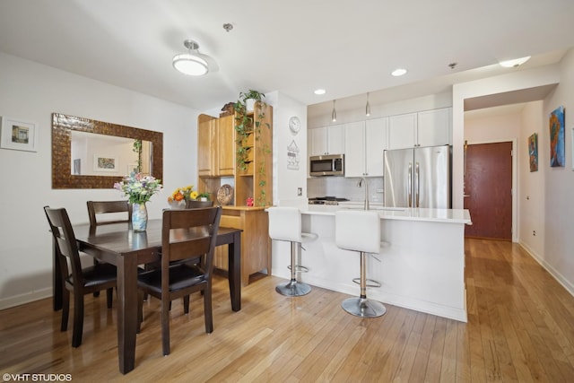 dining room with light wood finished floors, recessed lighting, and baseboards