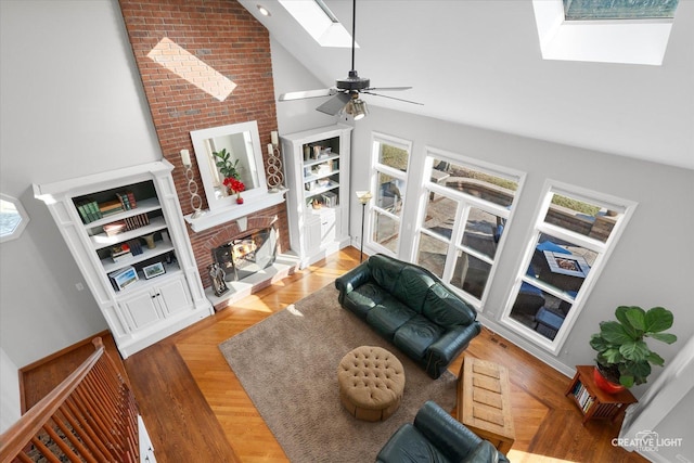 living room with a fireplace, ceiling fan, vaulted ceiling with skylight, and a healthy amount of sunlight