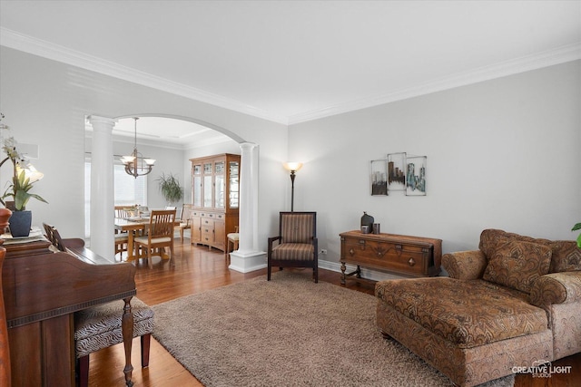 living room featuring an inviting chandelier, decorative columns, hardwood / wood-style flooring, and crown molding