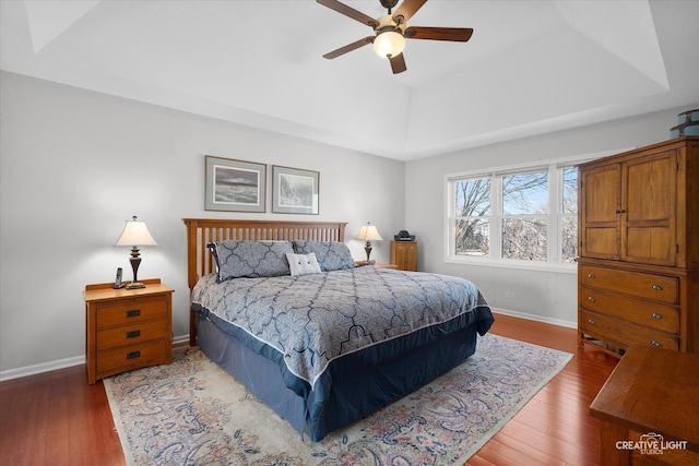 bedroom featuring ceiling fan, hardwood / wood-style floors, and a raised ceiling