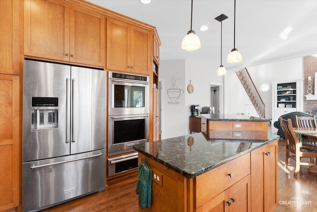 kitchen featuring stainless steel appliances, a center island, dark stone countertops, and pendant lighting