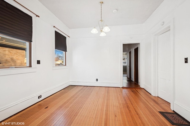 unfurnished room with baseboard heating, light hardwood / wood-style flooring, and a chandelier