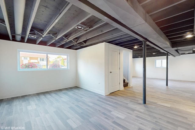 basement with a healthy amount of sunlight and light hardwood / wood-style floors