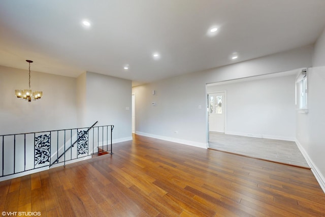 empty room featuring hardwood / wood-style flooring and an inviting chandelier