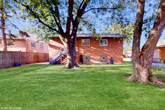 rear view of property with central AC and a lawn