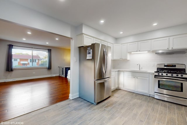 kitchen with stainless steel appliances, white cabinetry, sink, and tasteful backsplash