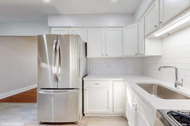 kitchen with sink, stainless steel fridge, white cabinetry, and backsplash