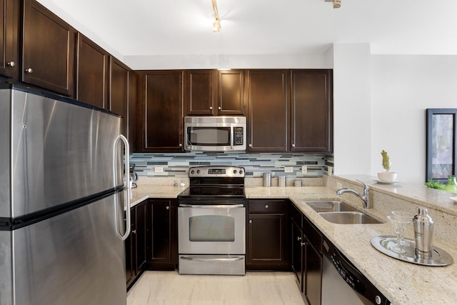 kitchen featuring appliances with stainless steel finishes, tasteful backsplash, light stone counters, and sink