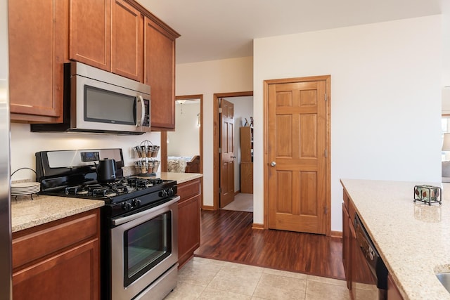 kitchen with light tile patterned floors, appliances with stainless steel finishes, and light stone counters