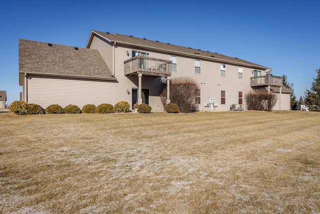 rear view of property featuring a balcony and a yard