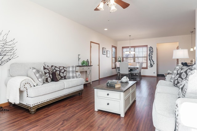 living room with dark hardwood / wood-style flooring and ceiling fan with notable chandelier