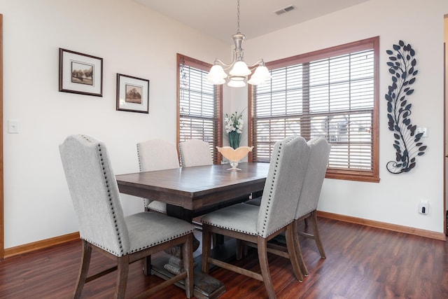 dining space with dark hardwood / wood-style floors, an inviting chandelier, and a healthy amount of sunlight