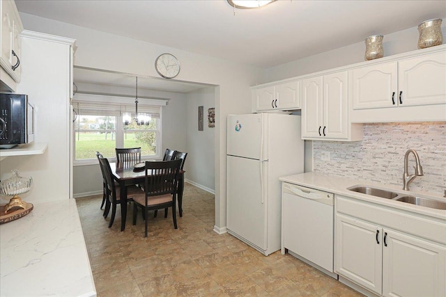 kitchen with white appliances, hanging light fixtures, an inviting chandelier, white cabinets, and sink