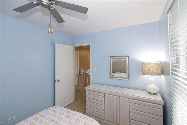 bedroom with ceiling fan, light colored carpet, and multiple windows